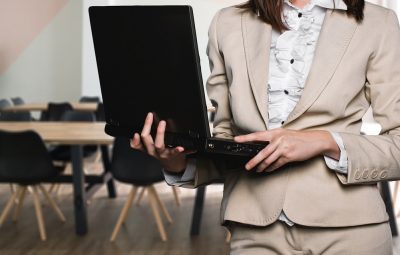 femme portant un tailleur clair avec un ordinateur portable dans les mains