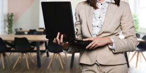 femme portant un tailleur clair avec un ordinateur portable dans les mains